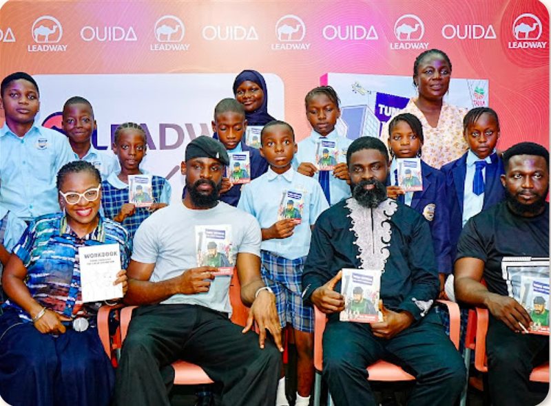 Children holding donated books with community guests